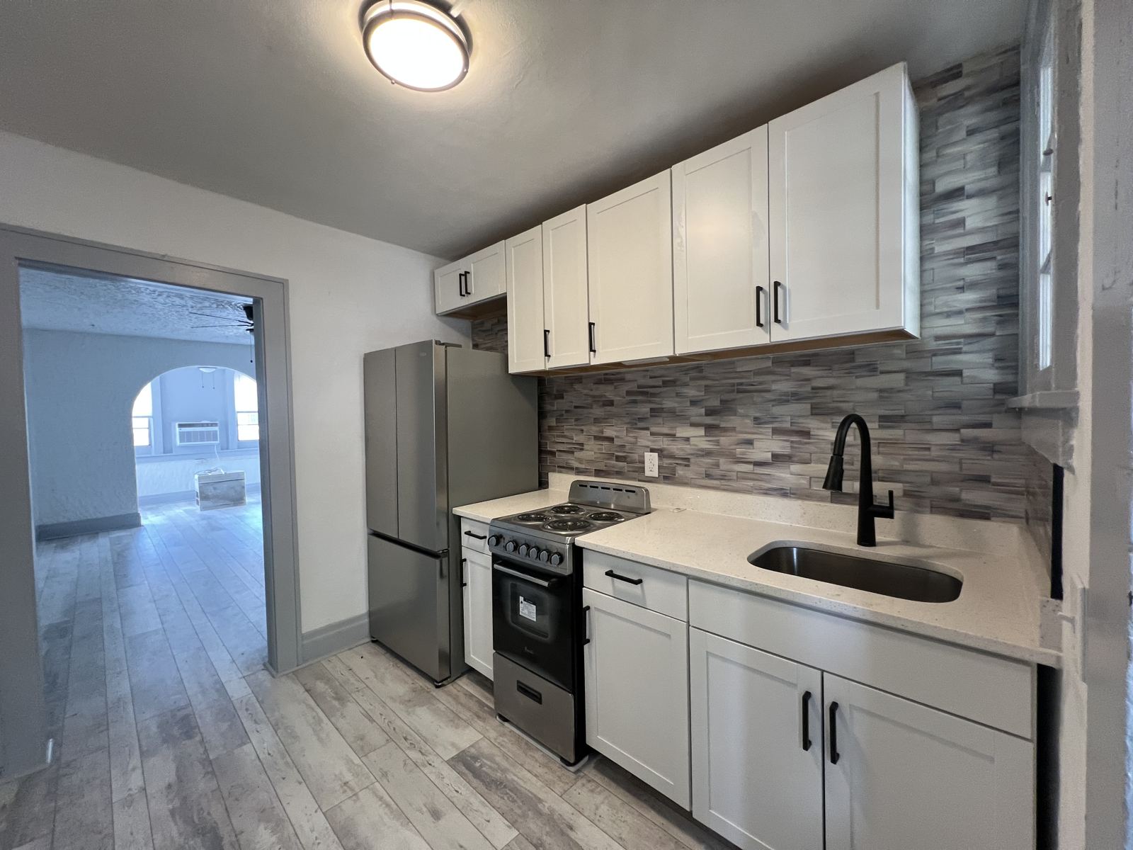 Apartment kitchen turned with white shaker cabinets, quartz and stainless appliances
