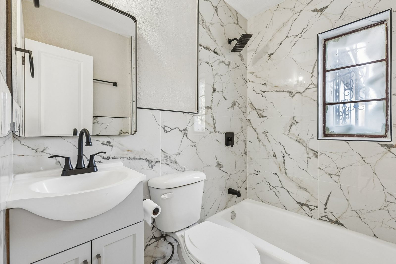 Mallory hall bath with full-height marble-look tile around the tub