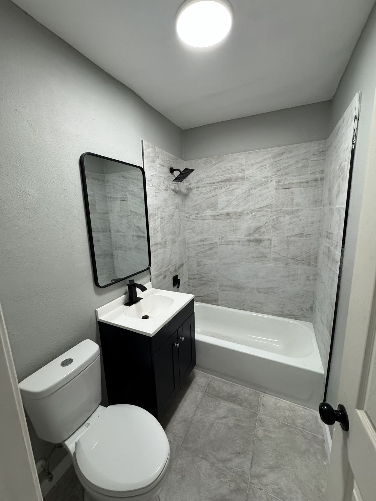 Apartment bathroom with new tile surround and black vanity