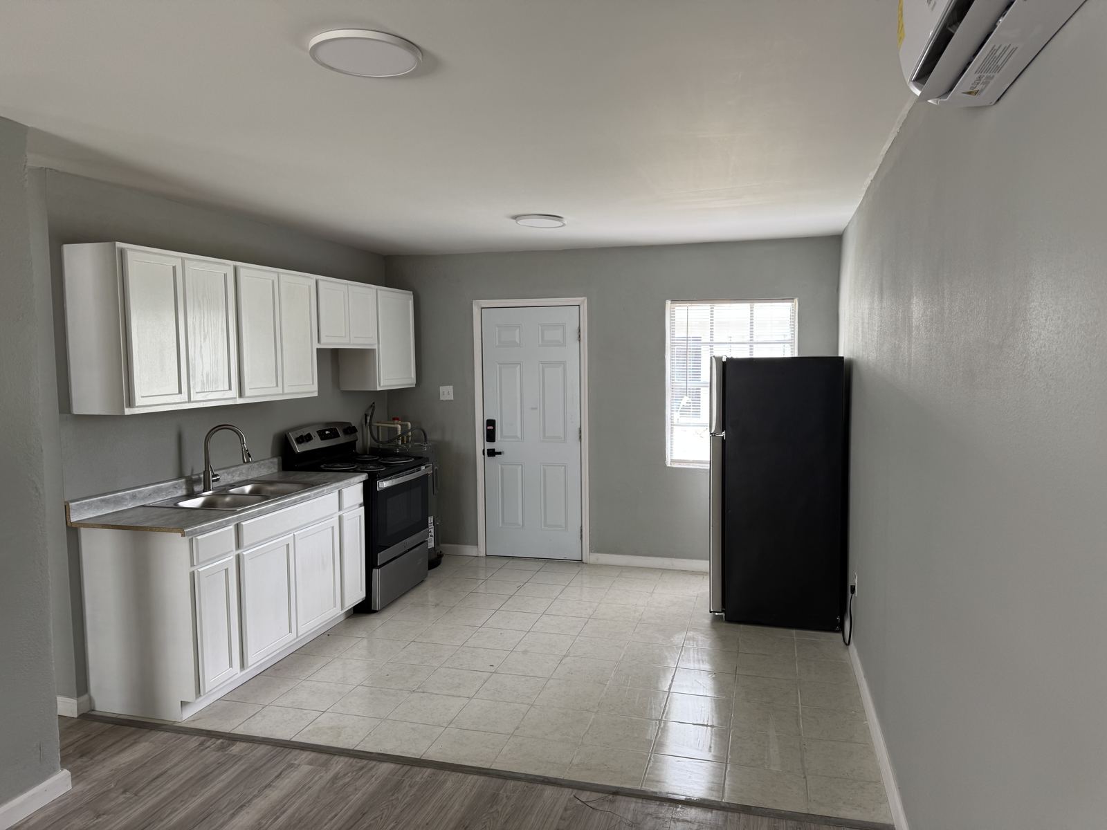 Same MLK apartment kitchen after the turn with white cabinets and new floors
